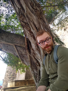 Jon sits near a banyan tree